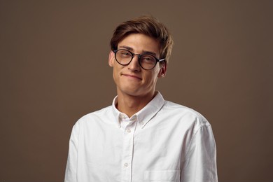 handsome man with glasses on a brown background white shirt
