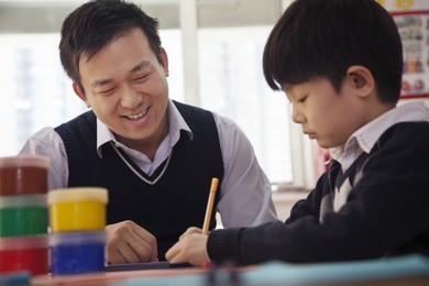 teacher helping schoolboy with arts and crafts