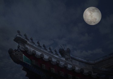 close-up of ornate roof tiles on chinese building with moon background