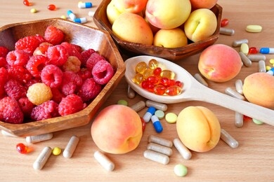 pills and capsules in wooden spoon and fresh tasty fruits on wooden background. nutrition multivitamins and supplement from fruits. organic food instead of pills concept. diet concept. top view