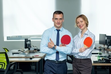 business man and woman, winners in play table tennis. office games during a working break. concept - office entertainment, leisure activity, sport, team building, teamwork.