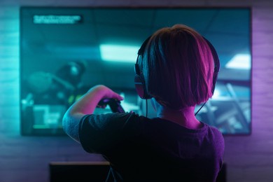 little boy playing video game in the dark room