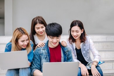university life. friends preparing for classes, sitting in university campus with books and devices.