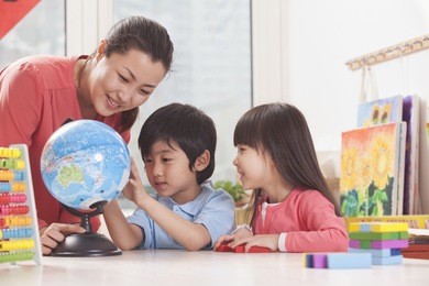 students and teacher looking at globe