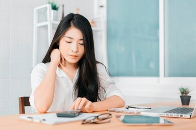 asian woman entrepreneur using a calculator calculating financial expense at home office, press calculator button finance analyzing  e-payment technology, shopaholic lifestyle, mobile application 