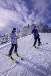 family is having fun in ski equipment on mountain slope. father and son are enjoying their time together. sunshine and snowfall at the same time. active lifestyle and cool family vacations concepts.
