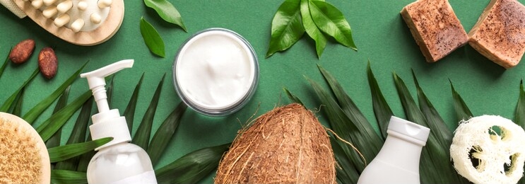 organic body and hair care products with green leaves and coconut on green background, trendy layout, eco beauty, spa and healthy lifestyle concept, banner.
