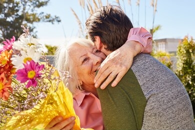 mother hugs her son and thanks for the flowers on mother's day