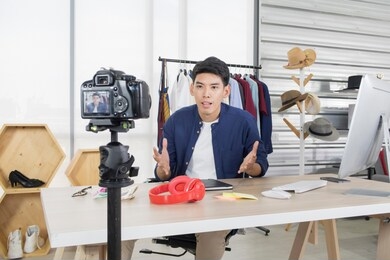 young handsome happy asian man sharing content on live streaming make video broadcast with internet subscribers. business, startup, e-commerce, social media, marketing online concept.