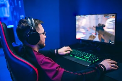 professional gamer playing online games tournaments pc computer with headphones, blurred red and blue background.