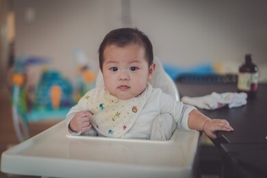 asian 6 months baby boy sitting high chair at home