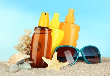 bottles with suntan cream and sunglasses, on blue background