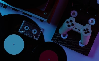 retro media and entertainment items 80s. vinyl player, video, audio cassettes, 3d glasses, gamepad. neon light. top view