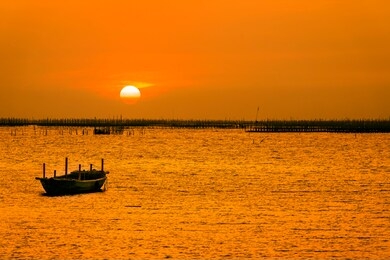 beautiful summer sunset concept. the sunset at the scene is the oyster farm and the little boat. boat on the sea beach at sunrise time.