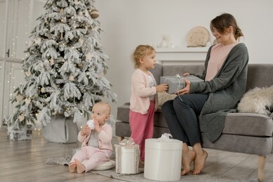 family christmas morning in a bright minimalistic living room near the christmas tree. casual, simple lifestyle.