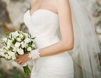 caucasian bride holding wedding bouquet of various flowers.