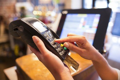 woman hand with credit card swipe through terminal for sale in restaurant