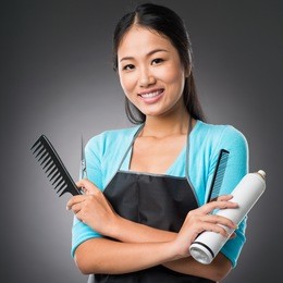 portrait of a young female stylist with necessary equipment isolated on grey