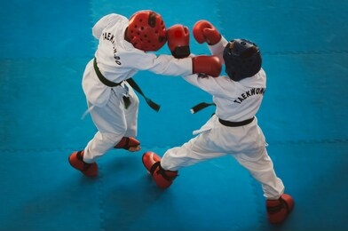 martial arts - taekwondo. kids in traditional kimano, hard hats and gloves. sports duel. for atmospheric added film noise effect. text: taekwondo is the name for martial art.