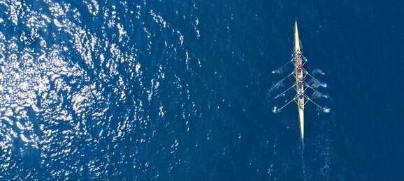 aerial drone ultra wide photo of sport canoe with young team of athletes practising in deep blue open ocean sea