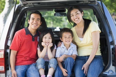 family sitting in back of van smiling