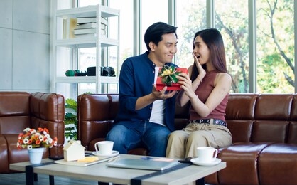 a handsome asian man is giving gift to his girlfriend for anniversary on valentine's day