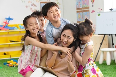 kindergarten teachers and children embrace together