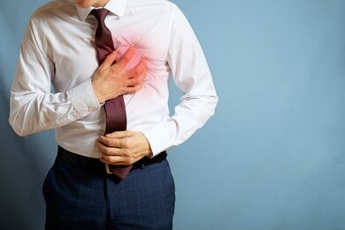 a man in trousers and a white shirt holds on to a heart, a symbol of a heart attack
