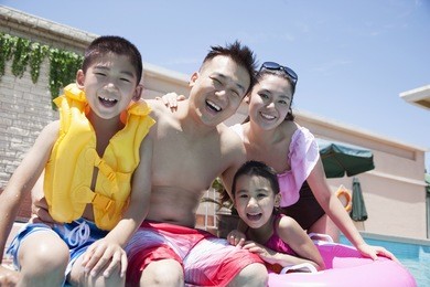 family smiling by the pool
