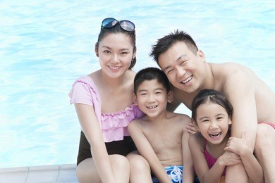 family smiling by the pool