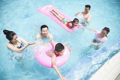 family and friends playing in water at the pool with inflatable tubes