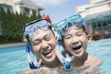 portrait of father and son with snorkeling equipment in pool