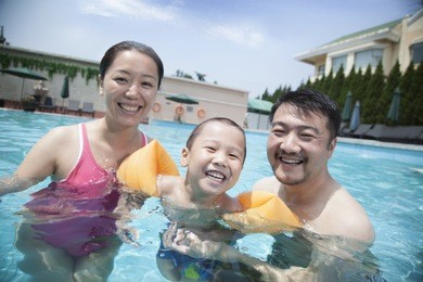 portrait of smiling young family in pool on vacation