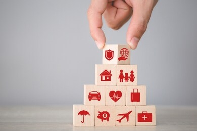 hand arranging flips wood block stacking with icon insurance: car,
 real estate and property, travel, finances, health, family and life,
insurance concept.