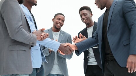 young business partners shaking hands to applause of employees