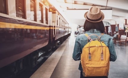 young asian woman traveler with backpack in the railway, backpack and hat at the train station with a traveler, travel concept. woman traveler tourist walking at train station