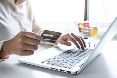 business woman using laptop and holding credit card for paying detail page display online shopping purchase and entry security code to inputting card information.