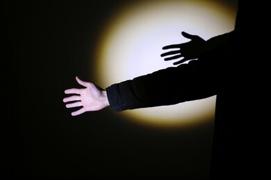 man's hand in spotlight on black background.