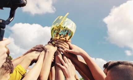 kids in sports team lift up the golden cup trophy after winning the final tournament match. children celebrate success in sports. winning championship in sports