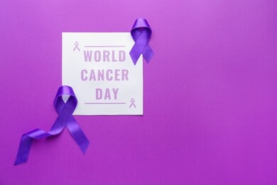 paper with text world cancer day and purple ribbons on color background