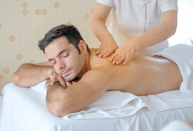 handsome man enjoy with thai masseuse massage to him and he lie on bed in spa room with day light.