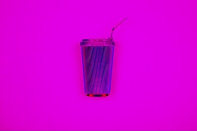 neon pink reusable iron coffee cup on lilac background. fragrant takeaway drink, layout for coffee. business and service concept. delicious morning hot drink. bright hipster trendy design.