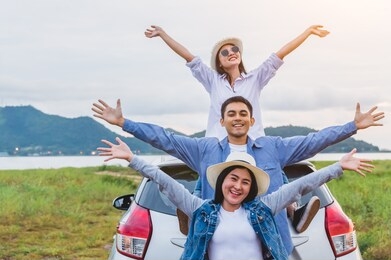 happy asian friends spread arms widely and breathed fresh air with happiness mood in on raod trip in car trunk. people lifestyle in long vacation trip concept. outdoors nature and transportation