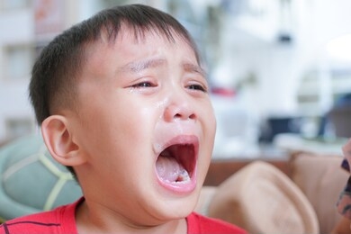 little child crying with mouth open wide, close up image of boy face open his mouth widely crying with tear and snot on his face