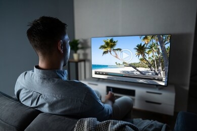 rear view of a man sitting on couch watching television