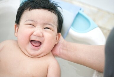 asian baby smiling and bathing with her mother in the bath room