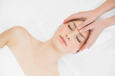 close up of hands massaging a beautiful womans forehead at