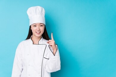 young chinese chef woman isolated showing number one with finger.