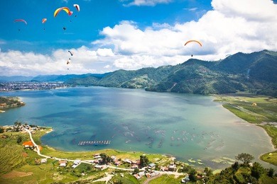 paraglider flying over the  fewa (phewa) lake in pokhara, nepal. 