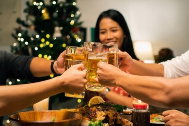 group of asian people have a dinner party and beer at home. they clink a glass of beer.